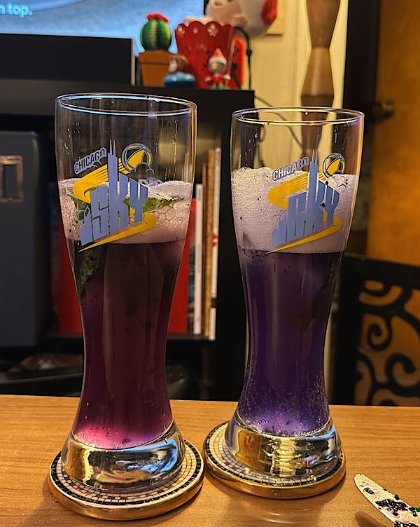 Deux verres remplis de liquide, l'un avec un liquide rose et l'autre avec un liquide violet foncé