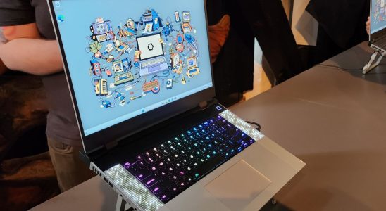 head on image of open Framework gaming laptop on presentation floor, abstract desktop background in Windows with RGB keyboard, speakers on side, chrome furnishing and slim black bezels