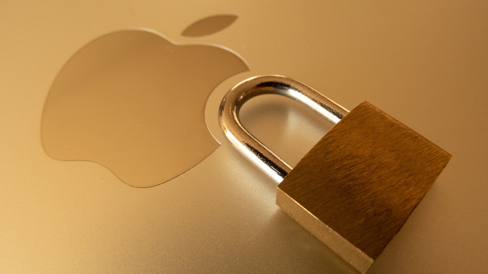 Un cadenas posé à côté du logo Apple sur le couvercle d'un ordinateur portable Apple doré.