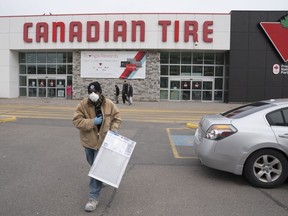 Un homme portant un masque sort d'un magasin Canadian Tire à Toronto le mercredi 18 mars 2020.