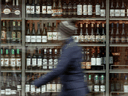 Une personne passe devant des étagères de bouteilles d'alcool exposées dans une LCBO à Ottawa.