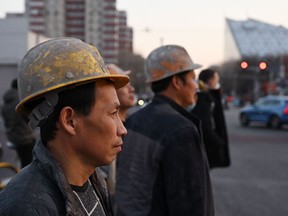 Des ouvriers du bâtiment attendent de traverser une route à Pékin le 2 mars 2023.