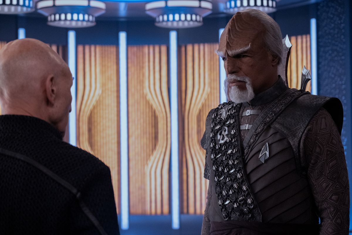 Un Worf plus âgé (Michael Dorn) debout et parlant à Picard (Patrick Stewart)