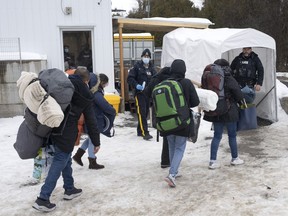 Une famille de demandeurs d'asile colombiens est accueillie par des agents de la GRC après avoir traversé la frontière à Roxham Road vers le Canada depuis Champlain, New York, le jeudi 9 février 2023.