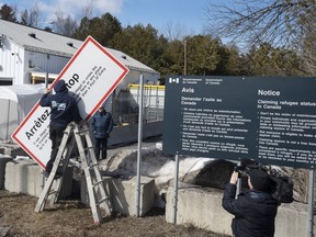 Les travailleurs retirent les panneaux d'avertissement à la frontière irrégulière de Roxham Road de New York au Canada le vendredi 24 mars 2023, à Champlain, NY