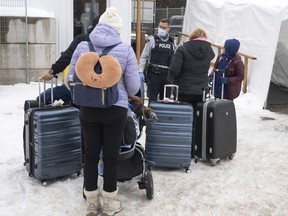 Une famille de demandeurs d'asile colombiens est accueillie par un agent de la GRC après avoir traversé la frontière à Roxham Road vers le Canada, le 9 février 2023 à Champlain, NY