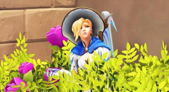 Mercy from Overwatch hiding in a bush. She is shrugging. She seems confused.