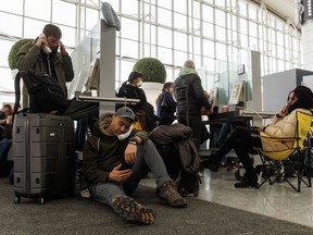 Les voyageurs attendent en attente pendant qu'ils essaient de parler avec leurs compagnies aériennes respectives à l'aéroport international Pearson de Toronto, car une importante tempête hivernale perturbe les vols à destination et en provenance de l'aéroport de Toronto, le 24 décembre 2022.