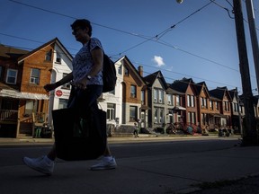 Une personne passe devant une rangée de maisons à Toronto le mardi 12 juillet 2022.