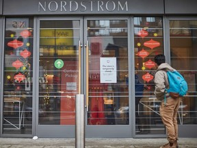 Un homme se tient devant le magasin Nordstrom, fermé pour faire du shopping en magasin au centre-ville de Toronto le 23 novembre 2020.