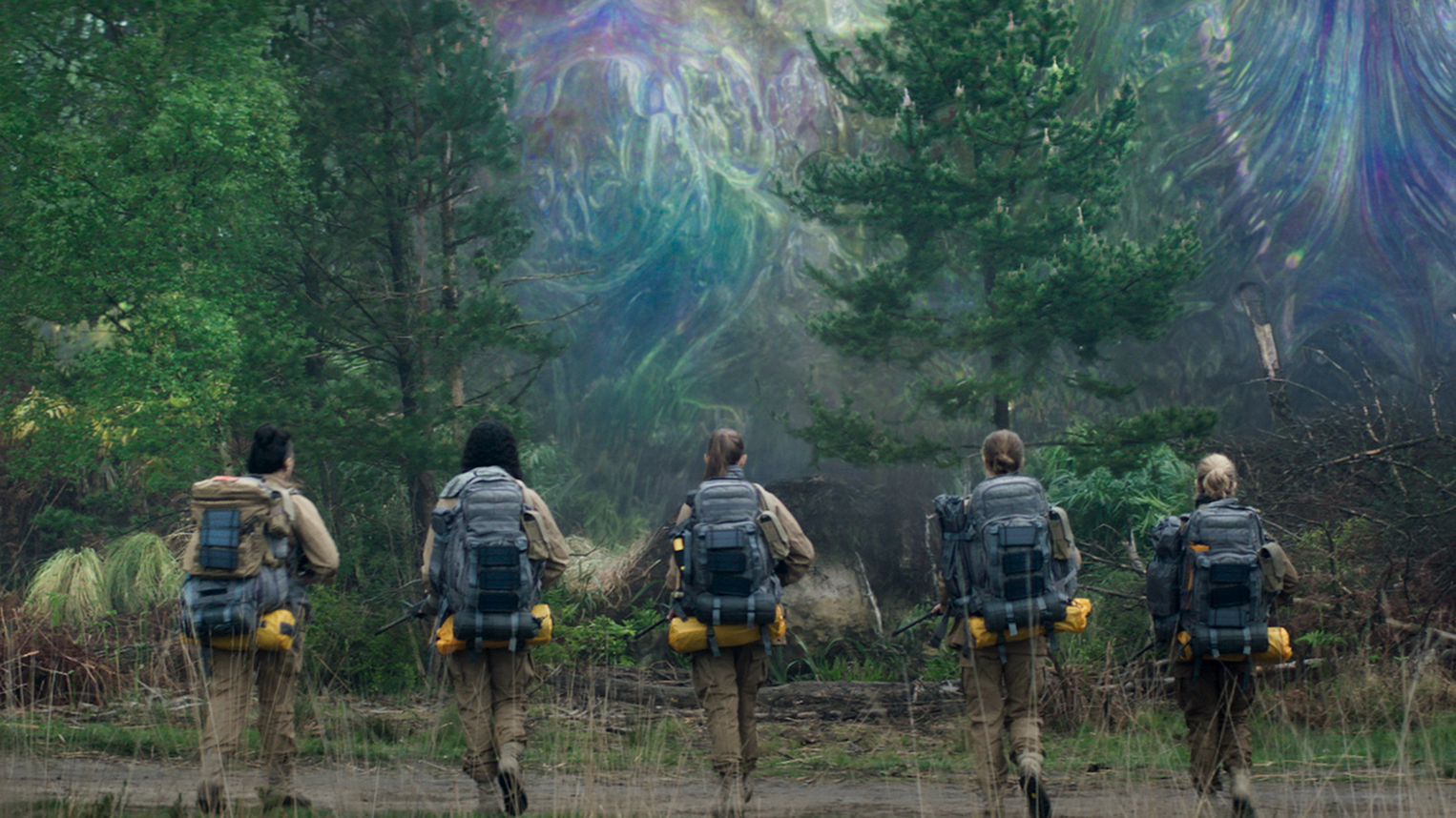 Une image tirée du film Annihilation dans laquelle un groupe de femmes scientifiques marchent vers une forêt scintillante.