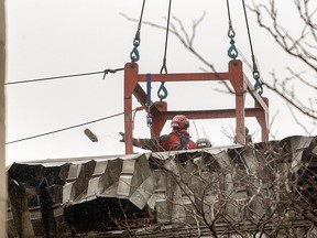 Des ouvriers enlèvent les décombres d'un bâtiment ravagé par un incendie à Montréal, le 23 mars 2023.