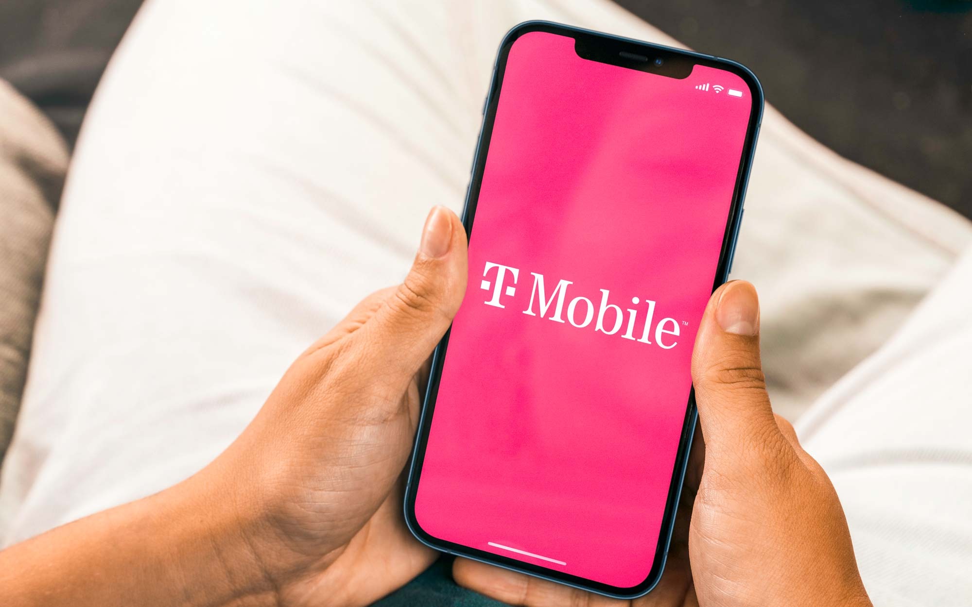 Une femme tenant un iPhone dans ses mains avec le logo T-Mobile superposé à l'écran