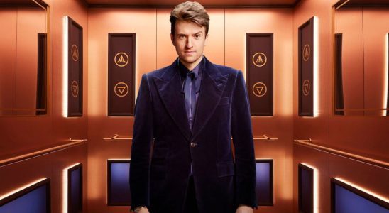Greg James stands in the elevator of Rise and Fall