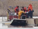 Un sac est soulevé d'un bateau des pompiers sur un quai lors de la recherche de victimes de noyade dans un marais à Akwesasne, à l'ouest de Montréal, le vendredi 31 mars 2023.