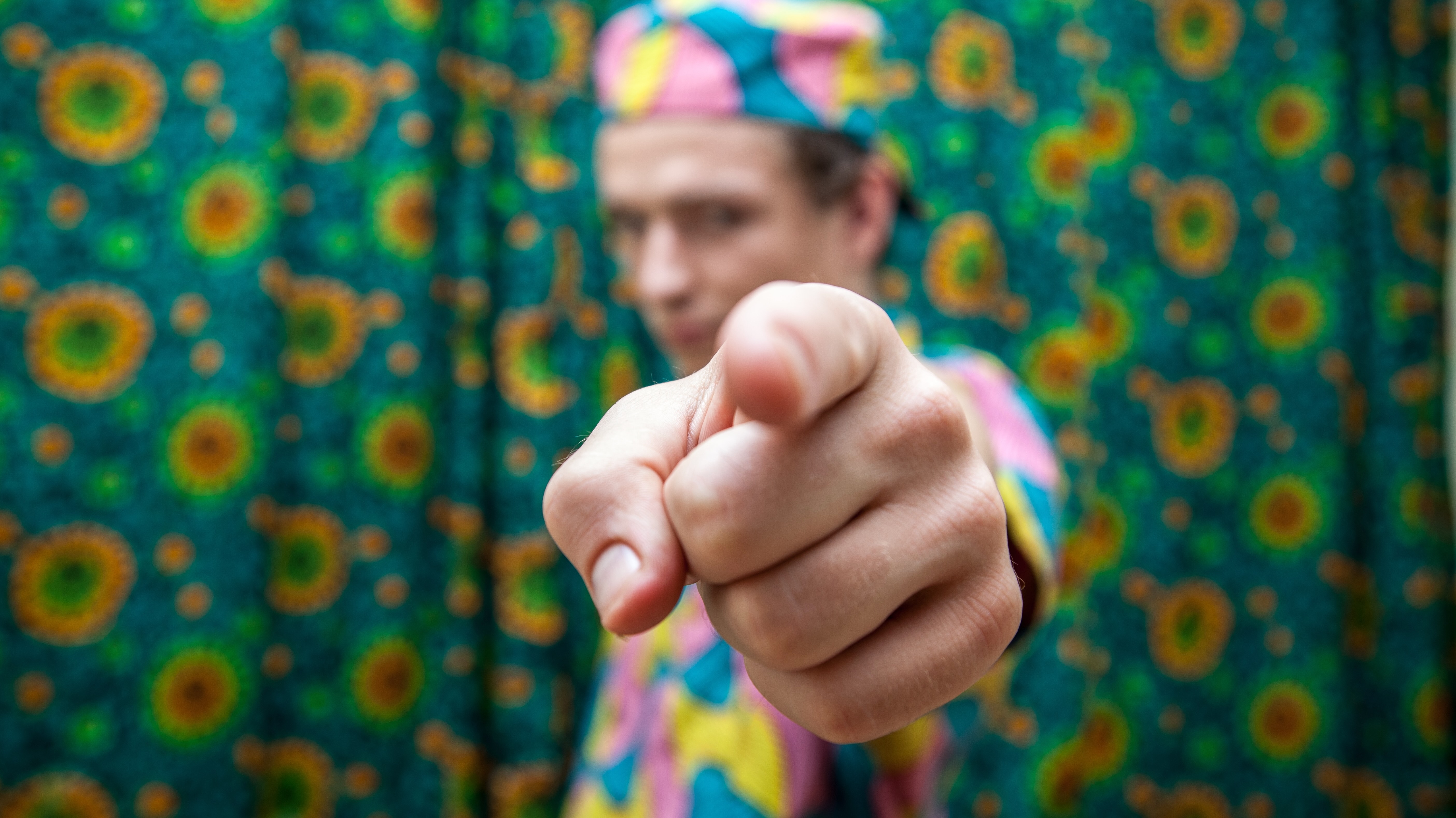 une personne vêtue de vêtements colorés vous pointant du doigt.