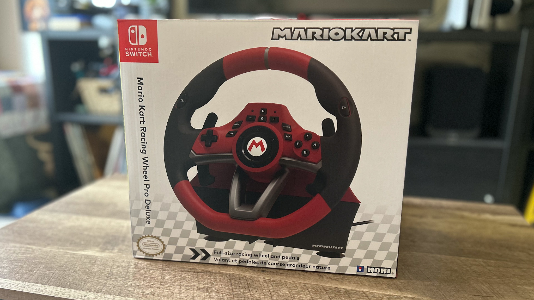 Hori Mario Kart Racing Wheel Pro Deluxe en boîte sur une table en bois