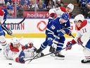Le défenseur des Canadiens Johnathan Kovacevic (26 ans) utilise sa main pour dégager la rondelle de l'attaquant des Maple Leafs de Toronto Mitch Marner (16 ans) au Scotiabank Arena le samedi 8 avril 2023 à Toronto. 
