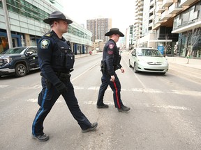 Le sergent Mike Anderson du Service de police de Calgary et le sergent par intérim Eric LeGreeley (bureau du shérif) marchent près du Sheldon Chumir Centre au centre-ville de Calgary le mercredi 13 avril 2023.