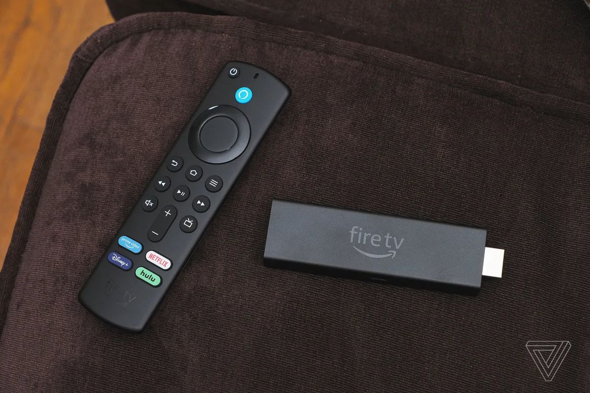 L'Amazon Fire TV Stick 4K Max et sa télécommande vocale posés sur un coussin de canapé.