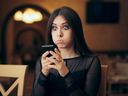 Jeune femme réagissant avec incrédulité à quelque chose sur son téléphone portable.