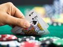 Main de jeu tenant des cartes, un roi et un as de pique, par des jetons de casino