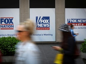Les gens passent devant les affiches de Fox News à l'extérieur du bâtiment du siège de News Corporation et de Fox News à Manhattan, à New York.
