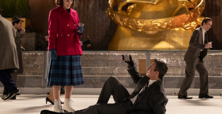 A man laying on an ice rink lifts his whiskey glass up at a woman in a plaid blue dress and magenta coat who stands looking down at him; still from "The Marvelous Mrs. Maisel"