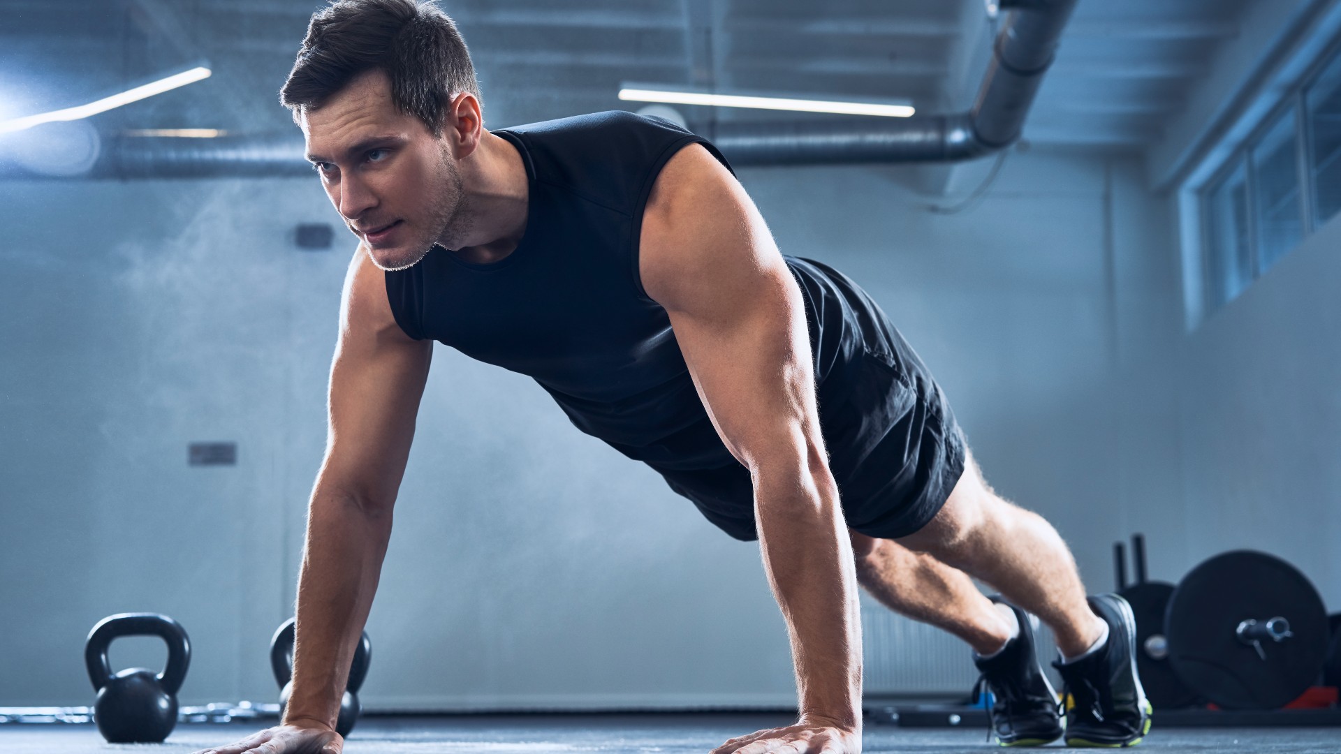 Homme exécutant un large push-up dans la salle de gym pendant l'entraînement de poids corporel