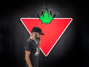 Un homme marche devant le logo de Canadina Tire