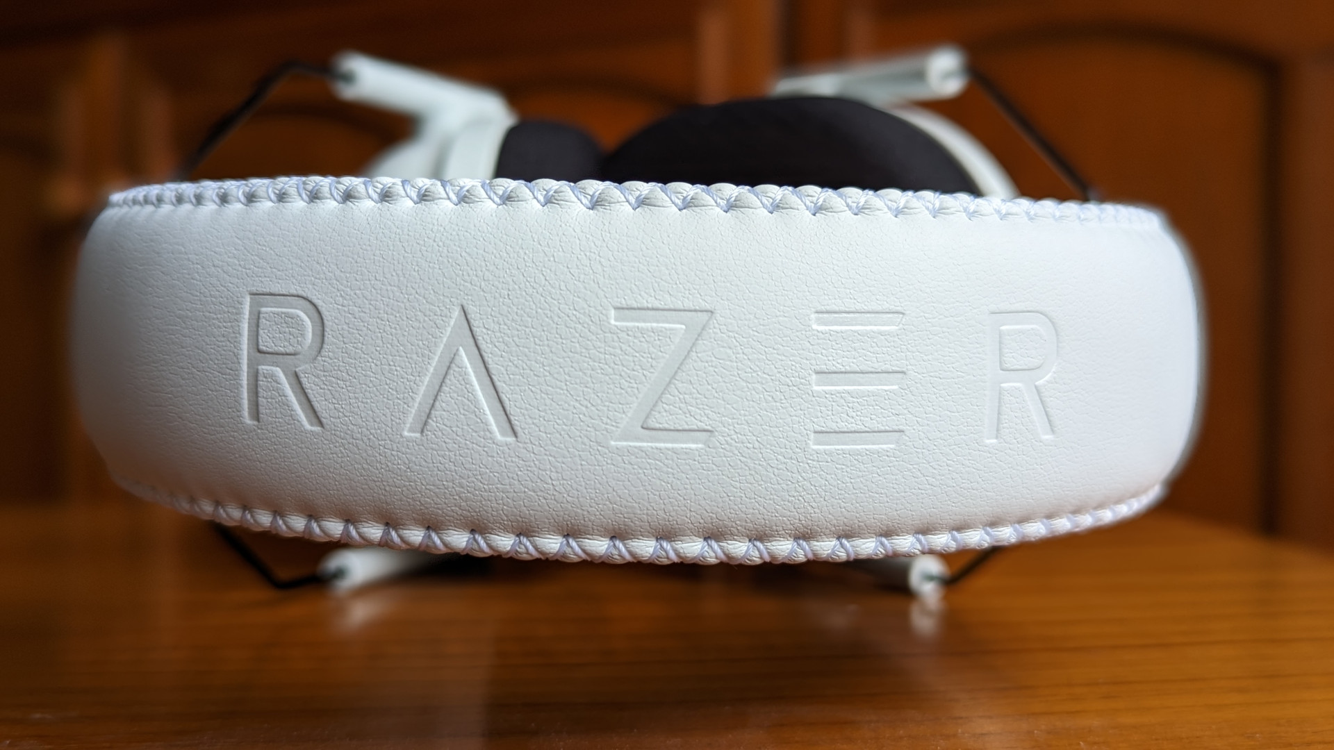 Revue Razer BlackShark V2 Pro : Un casque de jeu sans fil assis sur une surface en bois.  Le mot « RAZER » est incrusté sur le bandeau.