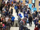Des centaines de passagers WestJet font la queue en attendant de réserver des vols annulés à l'aéroport international de Calgary le 20 décembre 2022.