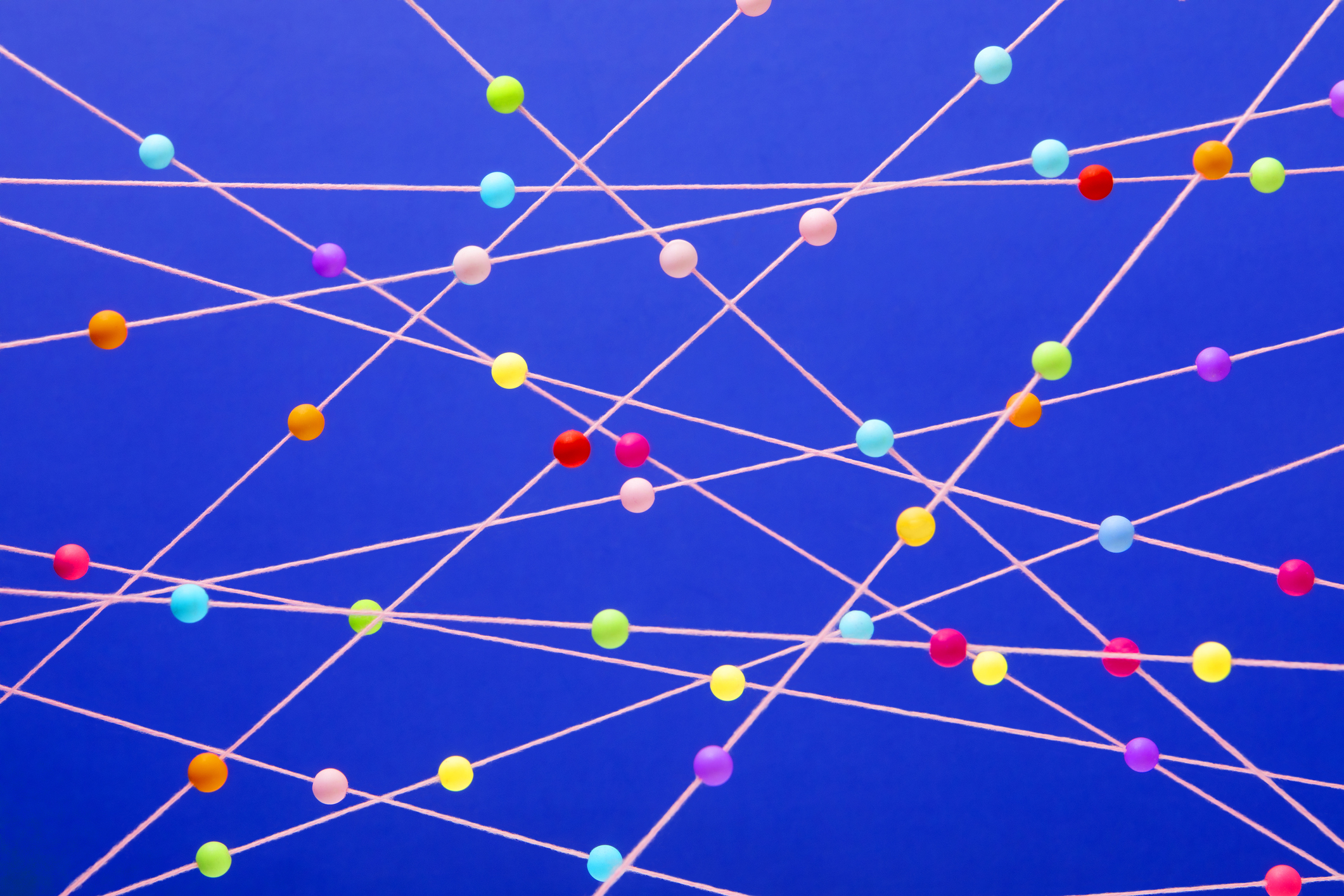 Boules multicolores lumineuses disposées au hasard sur fond bleu de cordes roses, utilisées dans le post sur Betterdata