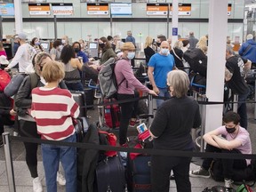 Des voyageurs font la queue à un comptoir d'enregistrement à l'aéroport Trudeau de Montréal, le mercredi 20 avril 2022.