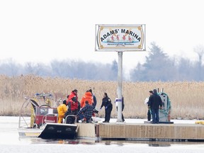 La police et les pompiers transportent un sac de leur bateau de recherche depuis le marais d'Akwesasne, au Québec, le 31 mars.