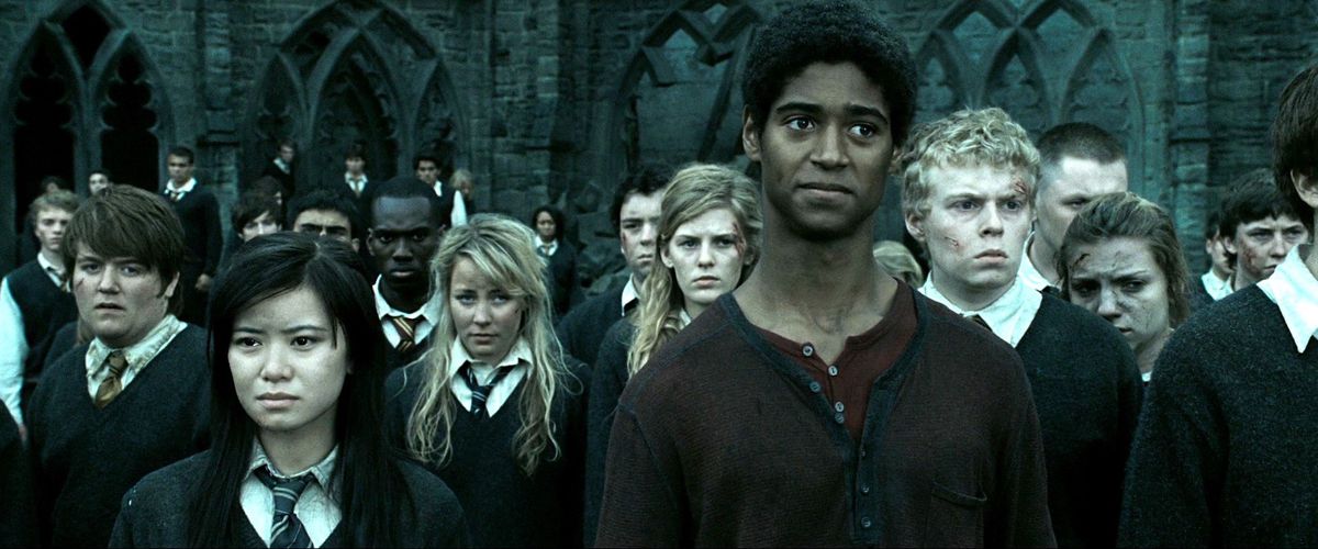 Cho Chang (Katie Leung), Dean Thomas (Alfred Enoch) et une foule d'autres élèves de Poudlard se tiennent devant l'école, battus et ensanglantés, dans Harry Potter et les Reliques de la Mort : Partie 2.
