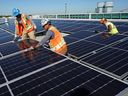 Des travailleurs de la ville d'Edmonton installent le plus grand réseau de panneaux solaires sur le toit du Canada au centre d'exposition d'Edmonton.