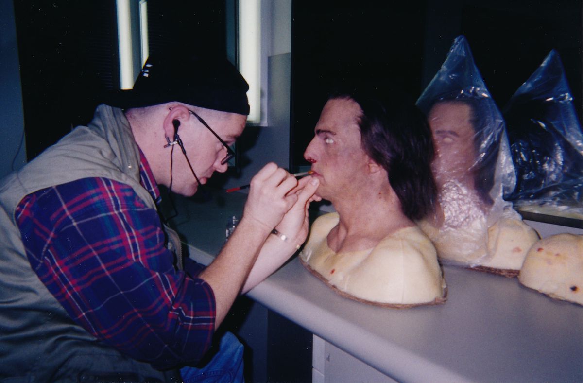 Une photo montre Mitchell Coughlin en train de peindre la bouche d'un masque posé sur un bureau.