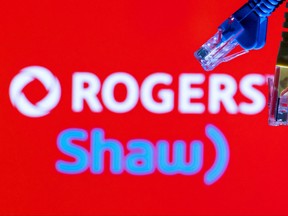 Des câbles Ethernet sont vus devant les logos de Rogers et de Shaw Communications dans cette illustration prise le 8 juillet 2022.