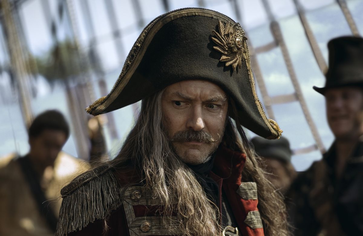 Jude Law dans le rôle du Capitaine Crochet dans Peter Pan &  Wendy, dans un gros plan souriant sur son bateau