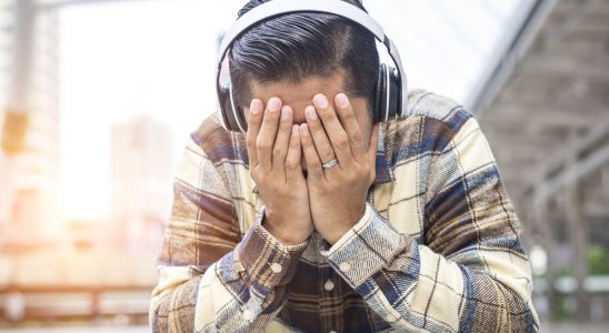 Person covering face while wearing headphones