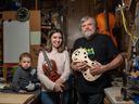 La violoniste ukrainienne Anastasiia Lykhosherstova et son fils Elisha, âgé de deux ans, posent pour une photo avec le luthier Ross Hill et le violon qu'il a offert à Lykhosherstova dans sa boutique de Calgary.