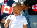 Brian Egbe agite un drapeau à Calgary lors d'une première cérémonie de citoyenneté en personne à l'amphithéâtre BMO du Stampede Park le 11 juillet 2022. Darren Makowichuk/Postmedia