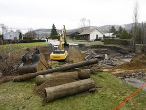 Une excavatrice travaille sur une rue qui a été coupée par la rivière Mares après que d'importantes inondations printanières ont frappé la région de Charlevoix, le mardi 2 mai 2023, à Baie-Saint-Paul, au Québec.