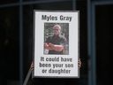 Une personne tient une pancarte avec une photo de Myles Gray, décédé à la suite d'une confrontation avec plusieurs policiers en 2015, avant le début d'une enquête du coroner sur sa mort, à Burnaby, en Colombie-Britannique, le lundi 17 avril 2023.