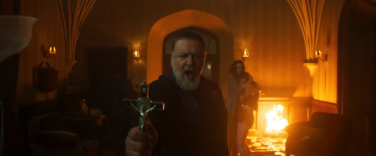 Russell Crowe tient une croix avec des flammes derrière lui dans L'Exorciste du Pape.