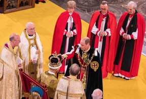 Le prince britannique William, prince de Galles, touche la couronne de Saint-Édouard sur la tête de son père, le roi britannique Charles III, lors de la cérémonie de couronnement du roi à l'intérieur de l'abbaye de Westminster, dans le centre de Londres, le 6 mai 2023.