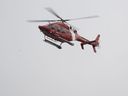 Un hélicoptère de la Garde côtière canadienne patrouille le fleuve à la recherche de deux pompiers disparus après que d'importantes inondations printanières ont frappé la région de Charlevoix, le mardi 2 mai 2023, à Baie-St-Paul, au Québec.