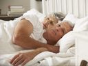 Femme plus âgée au lit avec son mari qui semble inquiet