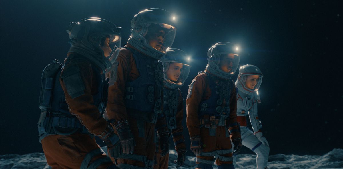 Cinq adolescents en combinaison spatiale marchant sur la surface de la lune. 